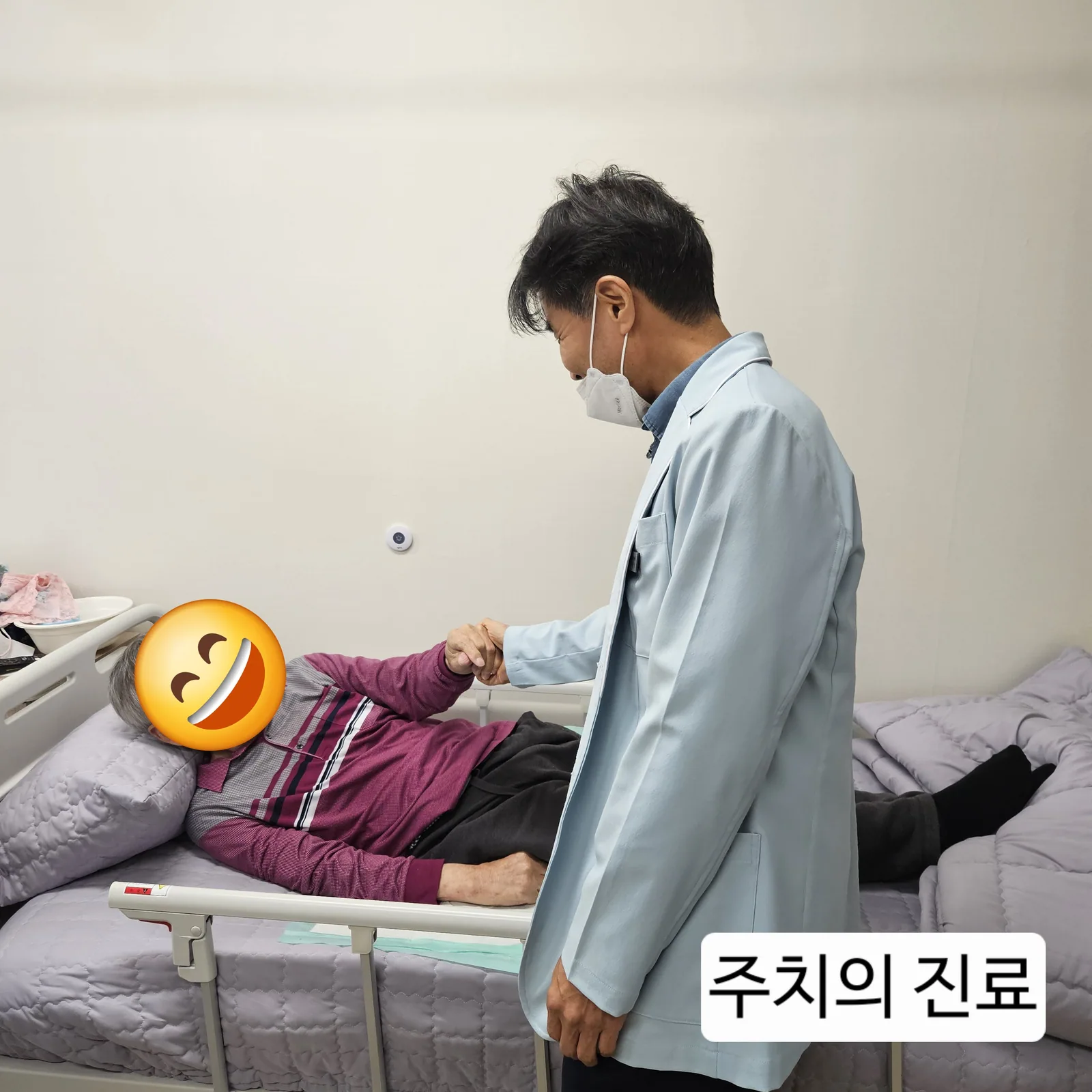 민들레요양원 주치의가 침상에 계신 어르신의 손을 잡고 살피는 진료 모습